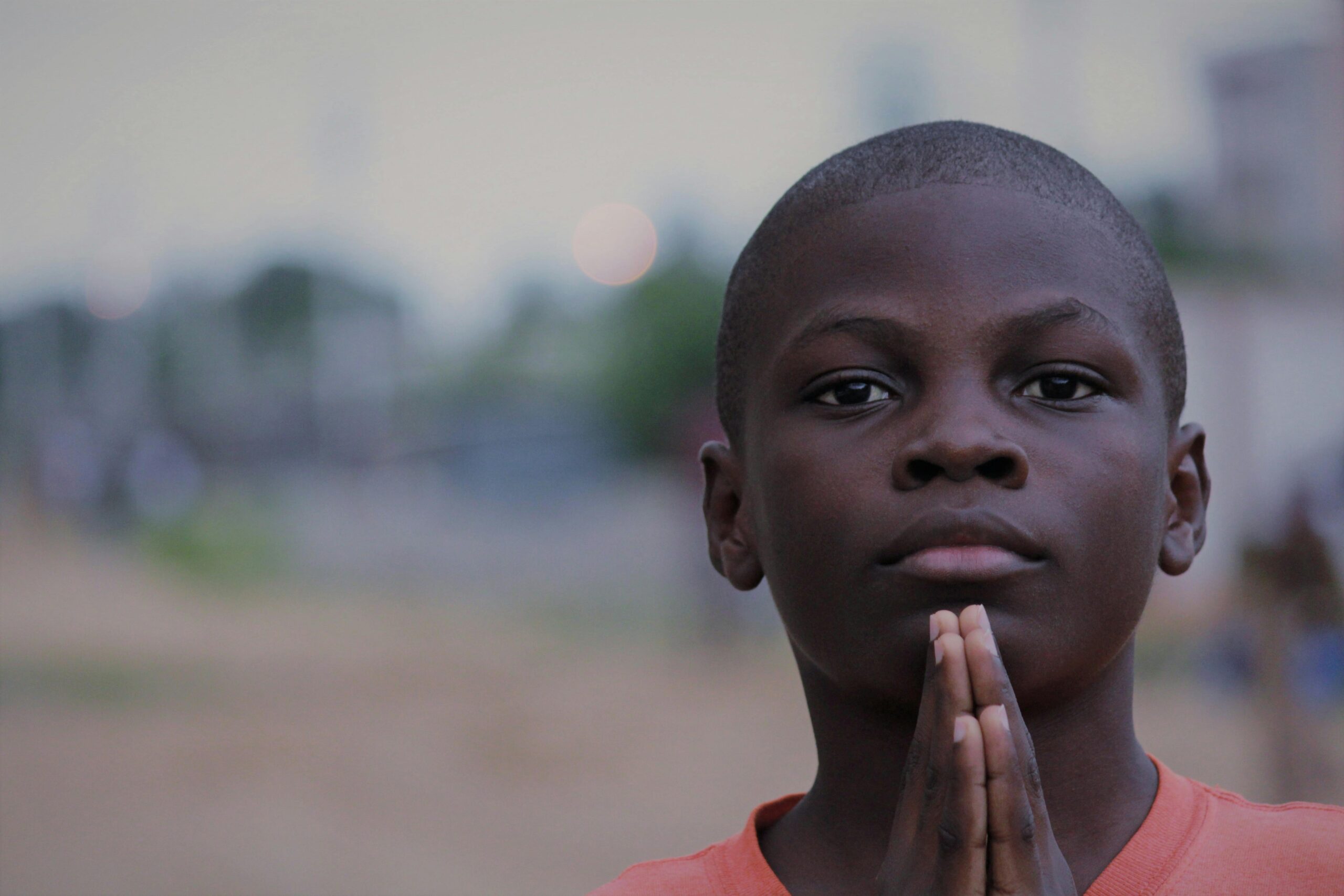 An image of an African child with both hands held close to the face.